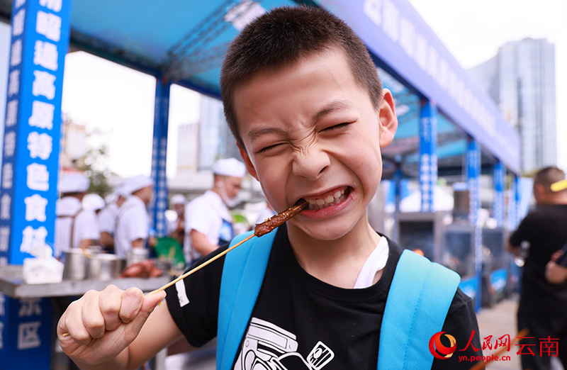 一名小孩爽爽“撸”起昭通小肉串。 赵连杰摄